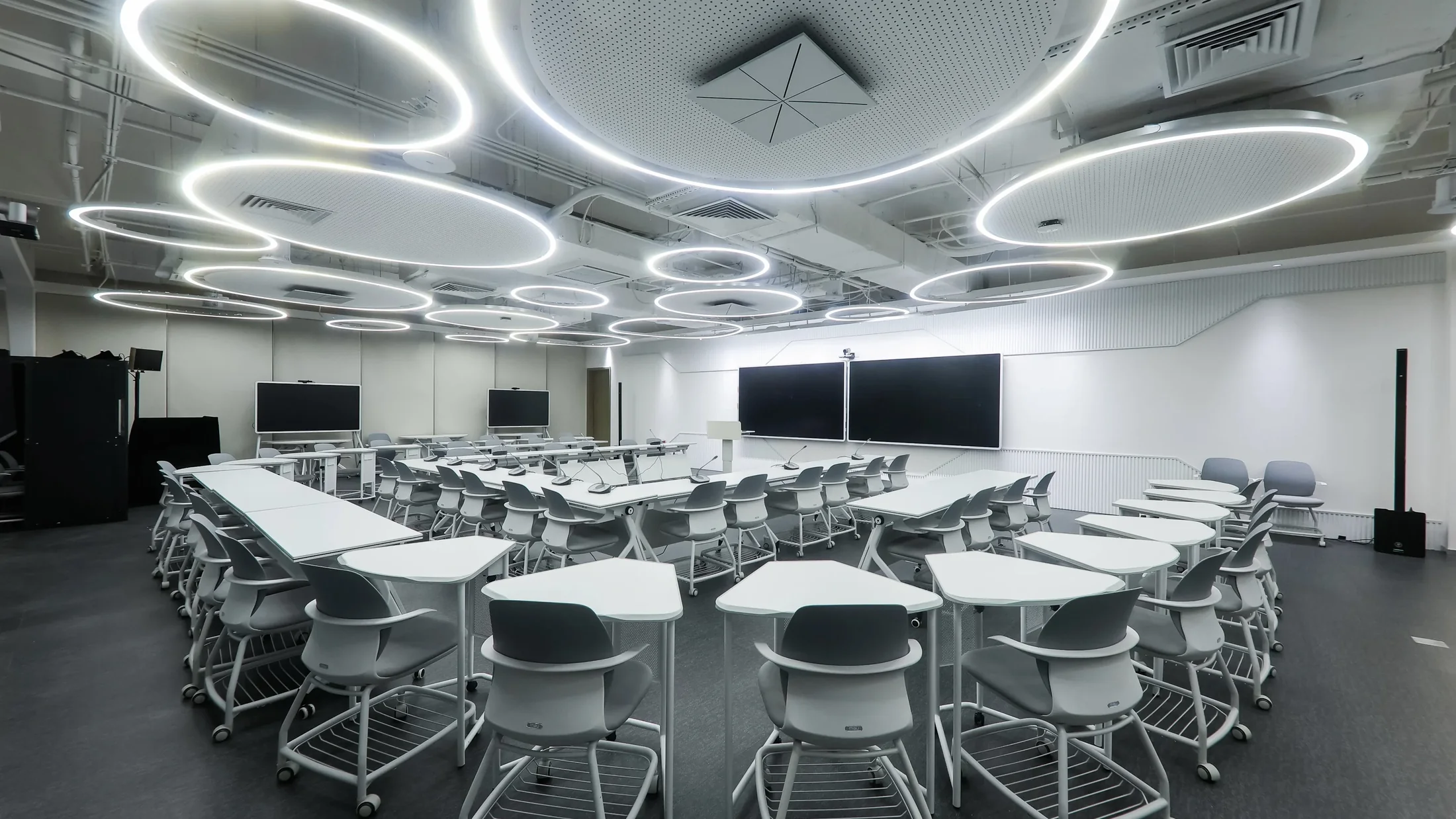 The Future Learning Space at Shanghai Foreign Language School: rows of white tables under round ceiling lights, with screens along the walls.