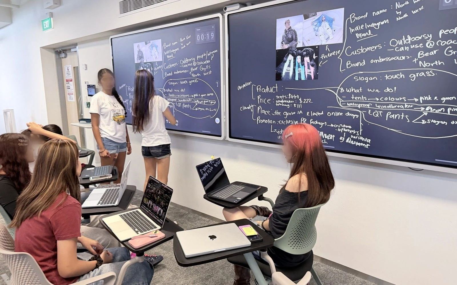 Temasek Polytechnic students working in groups beside two interactive screens covered in their brand plan.